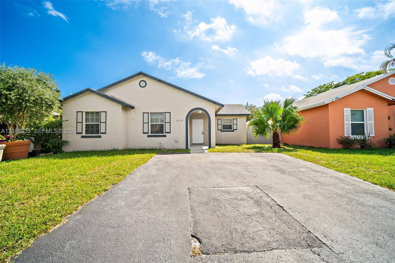 12752 SW 250th Terrace, Homestead, FL 33032 Single-story stucco exterior featuring an arched entryway, decorative shutters, and an asphalt driveway