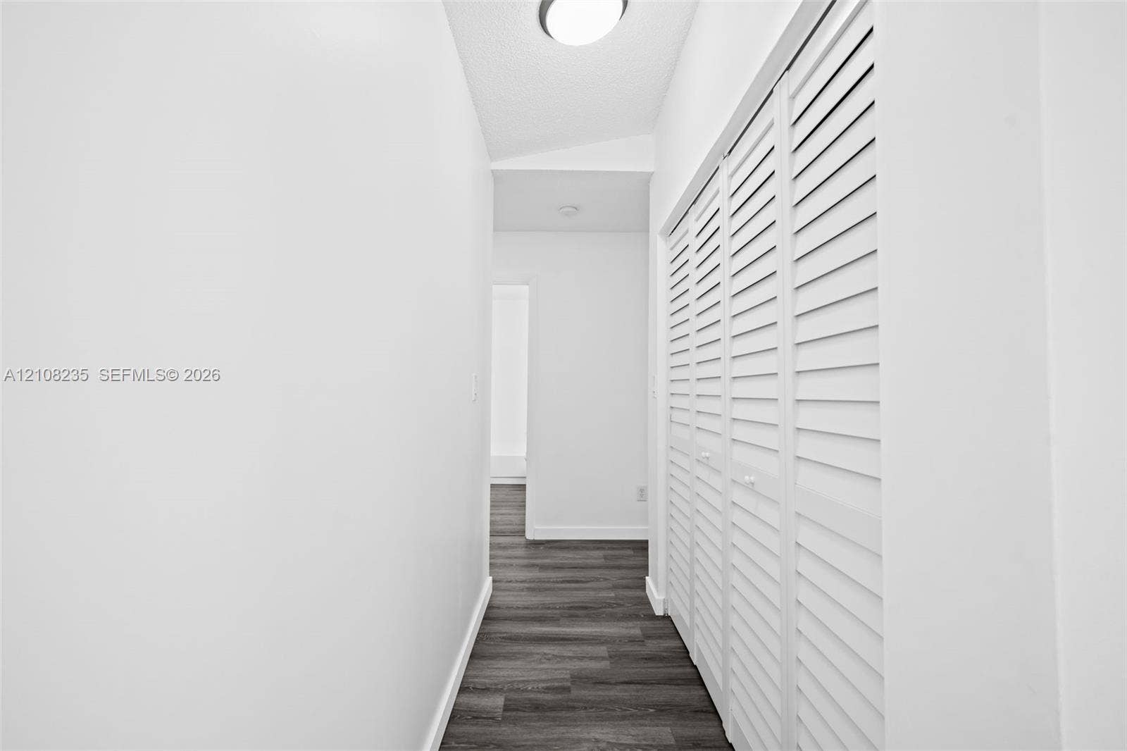 12752 SW 250th Terrace, Homestead, FL 33032 Hallway featuring wood-finish flooring and floor-to-ceiling white louvered bifold closet doors