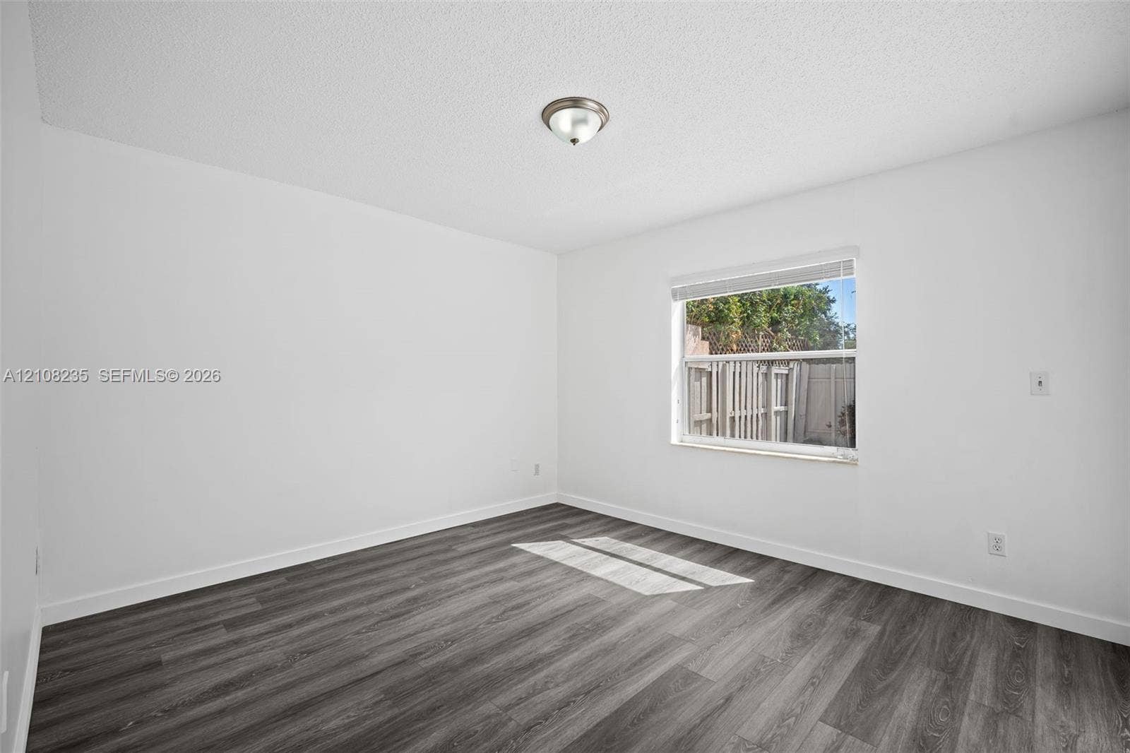 12752 SW 250th Terrace, Homestead, FL 33032 Room featuring wood-finish flooring, a single-pane window with white horizontal blinds, and a flush-mount ceiling light fixture