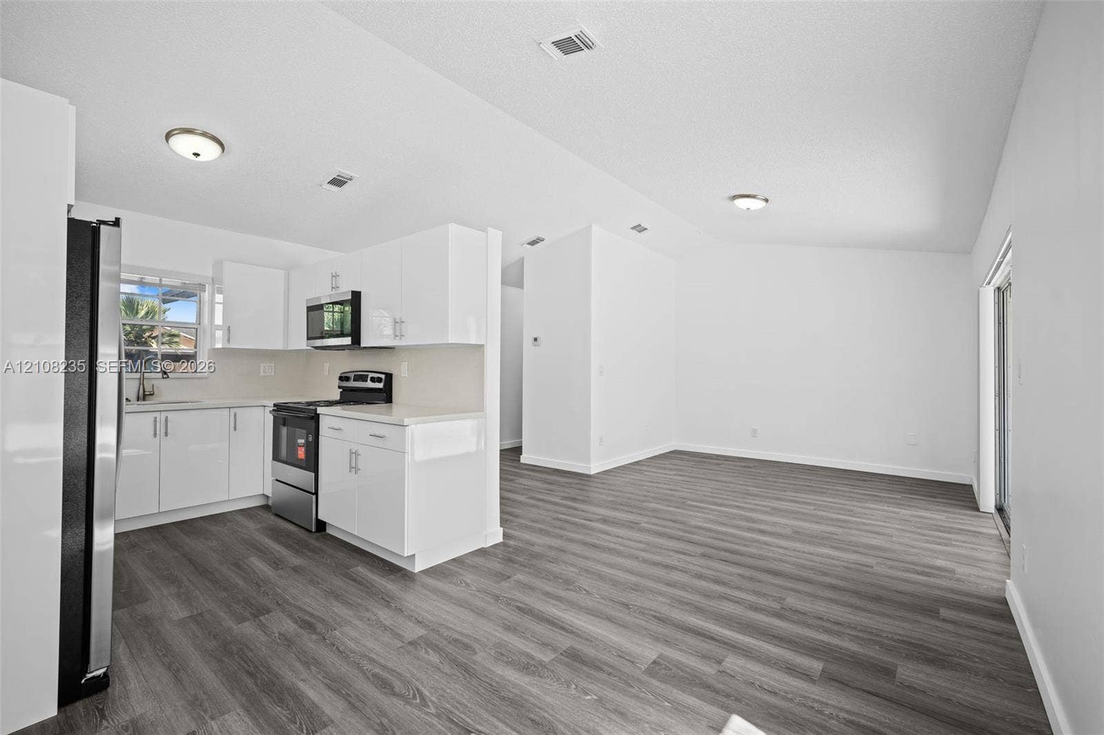 12752 SW 250th Terrace, Homestead, FL 33032 Kitchen featuring white cabinetry, solid-surface countertops, stainless steel appliances, and wood-finish flooring