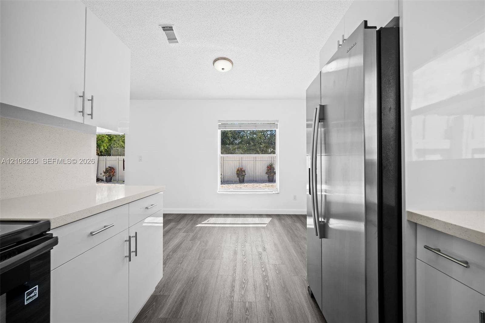 12752 SW 250th Terrace, Homestead, FL 33032 Kitchen featuring white flat-panel cabinetry, light-toned stone-surface countertops, wood-finish flooring, and a stainless steel side-by-side refrigerator
