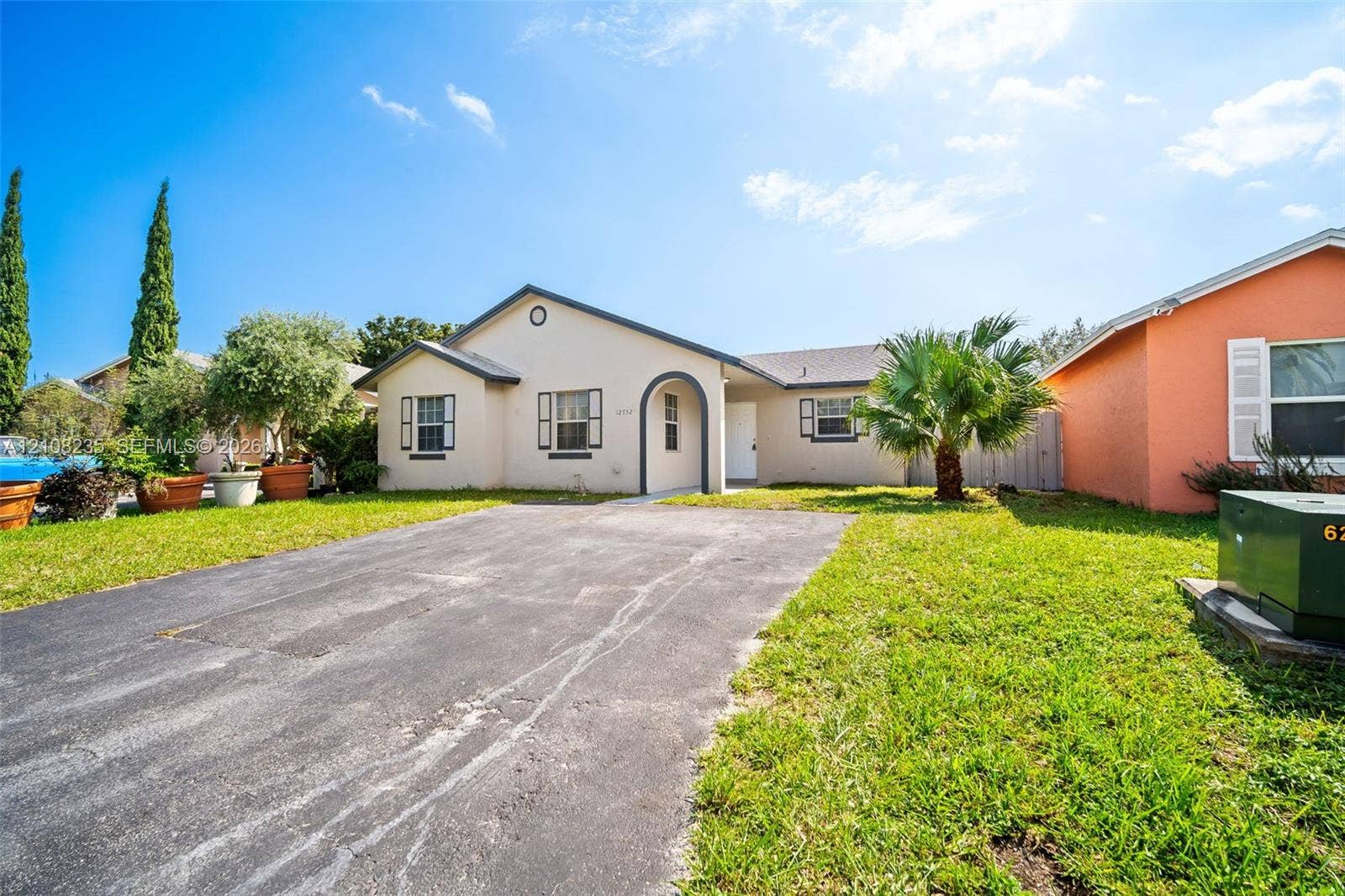 12752 SW 250th Terrace, Homestead, FL 33032 Single-story residence featuring a stucco exterior, arched entryway, shingle roof, and asphalt driveway
