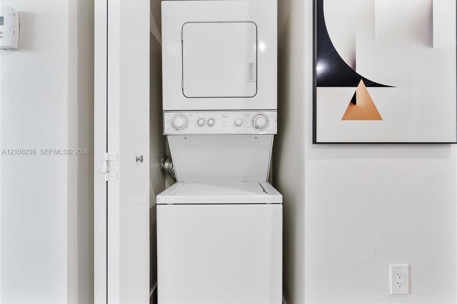 Stacked white laundry unit housed within a built-in closet