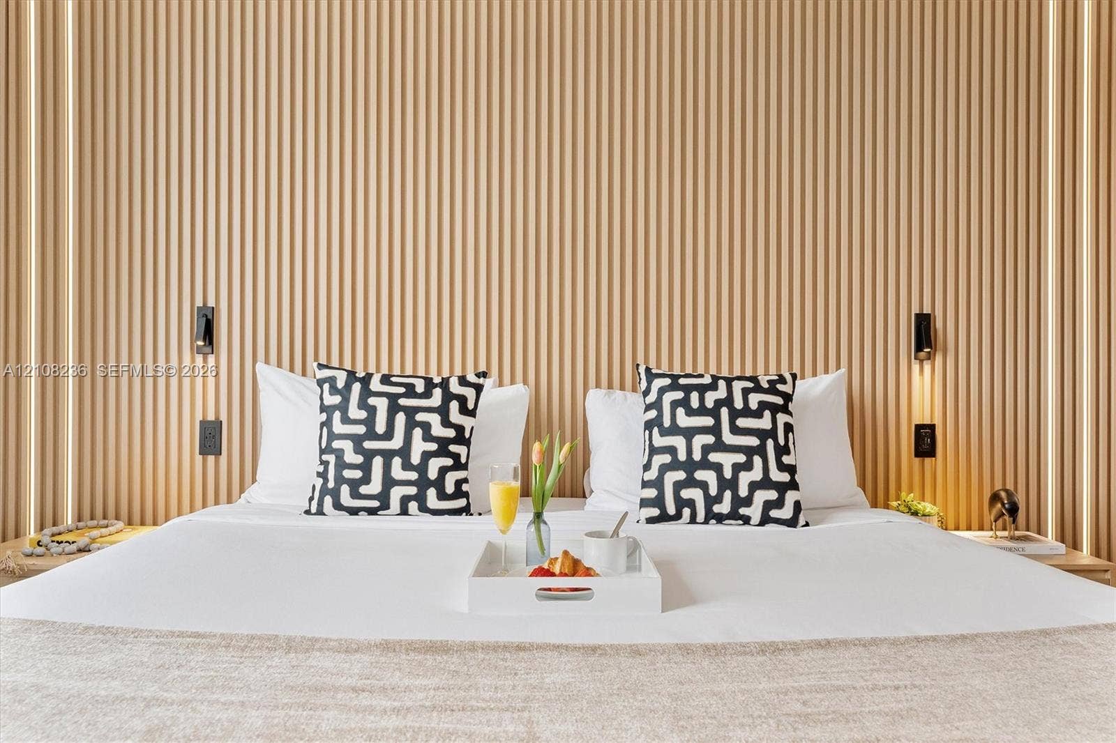 Vertical wood slat accent wall featuring integrated recessed LED lighting strips and wall-mounted reading lights
