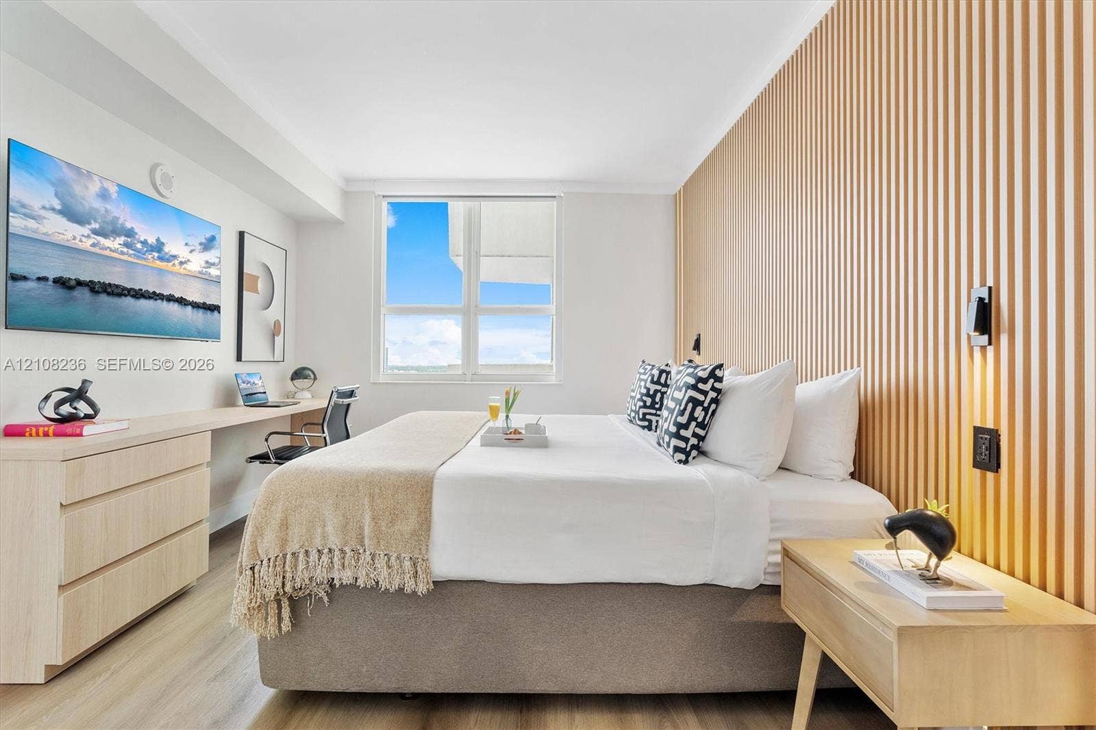 Slatted wood-finish accent wall, built-in light wood-finish desk, large window, and wood-finish flooring