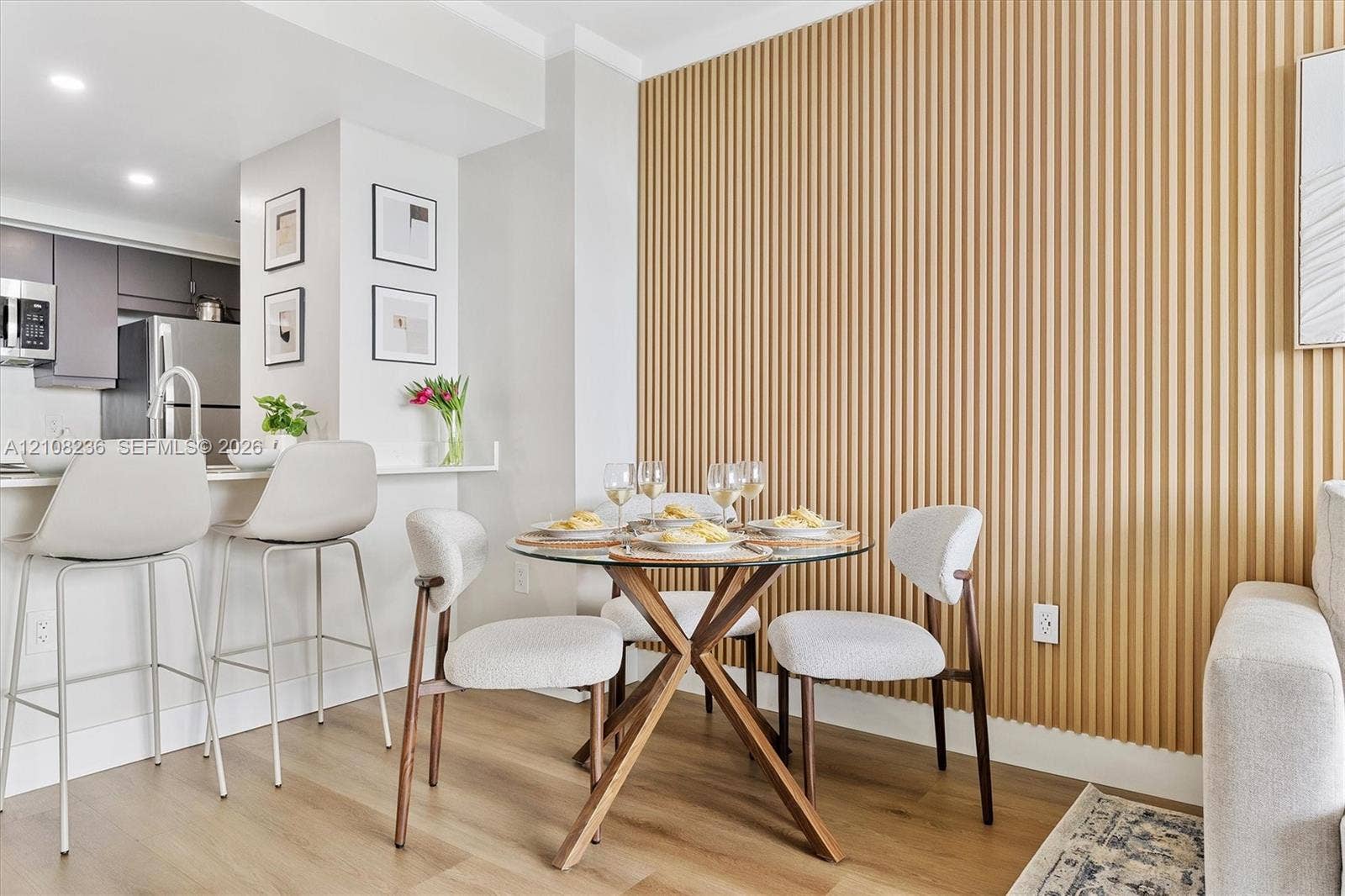 Vertical slatted wood-finish wall paneling, light-toned wood-finish flooring, recessed lighting, and built-in kitchen cabinetry featuring stainless steel appliances