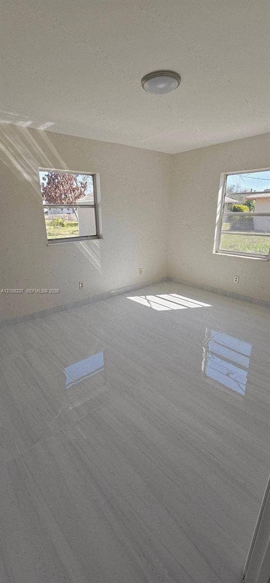 338 SW 8th Avenue SW, #., Vero Beach, Vero Beach, FL 32962 Neutral-toned interior space featuring light-colored tile flooring, smooth walls, two windows, and a circular flush-mount ceiling light fixture