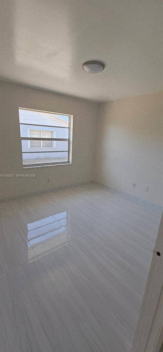 338 SW 8th Avenue SW, #., Vero Beach, Vero Beach, FL 32962 Interior space featuring high-gloss tile flooring, neutral wall paint, and a multi-pane horizontal sliding window with a flush-mount overhead light fixture
