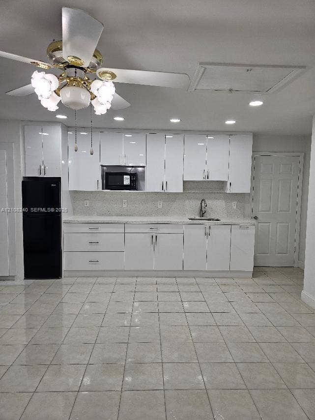 Glossy white cabinetry with modern hardware, stone-finish countertops, recessed ceiling lighting, tiled flooring, and a multi-light ceiling fan