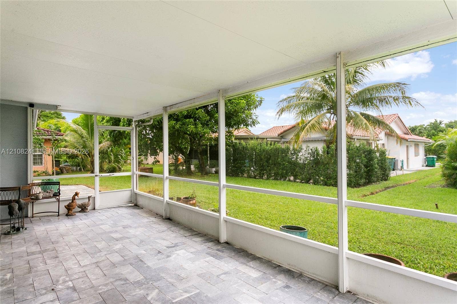 Screened-in patio featuring gray paver flooring, a solid roof, and metal framing
