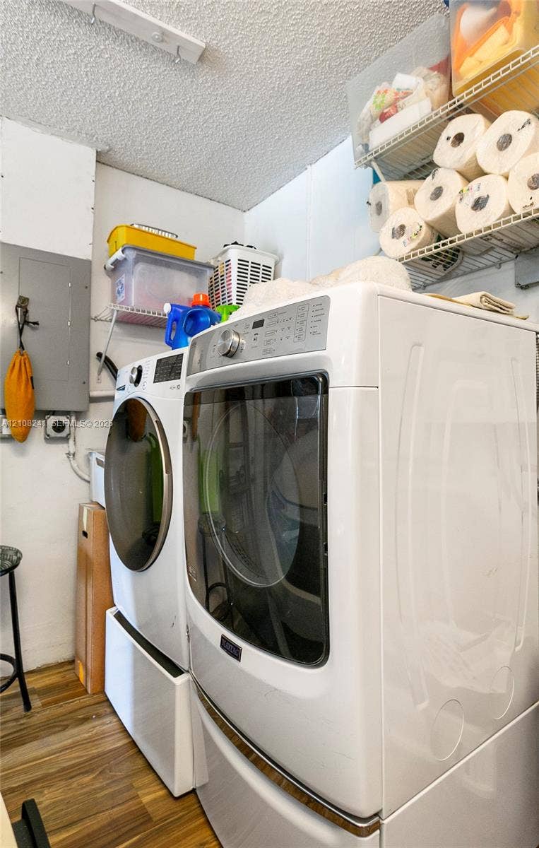Laundry area featuring wood-finish flooring, white appliances, and built-in wire shelving