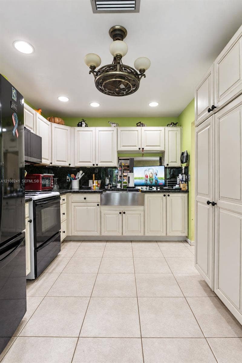 Kitchen featuring white cabinetry, stainless steel farmhouse sink, tiled flooring, recessed lighting, and a ceiling-mounted fixture