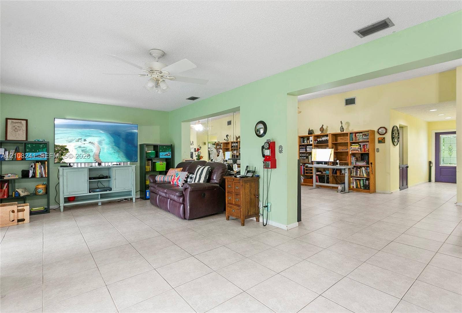 Spacious interior featuring ceramic tile flooring, built-in wooden shelving, and a ceiling fan with integrated lighting