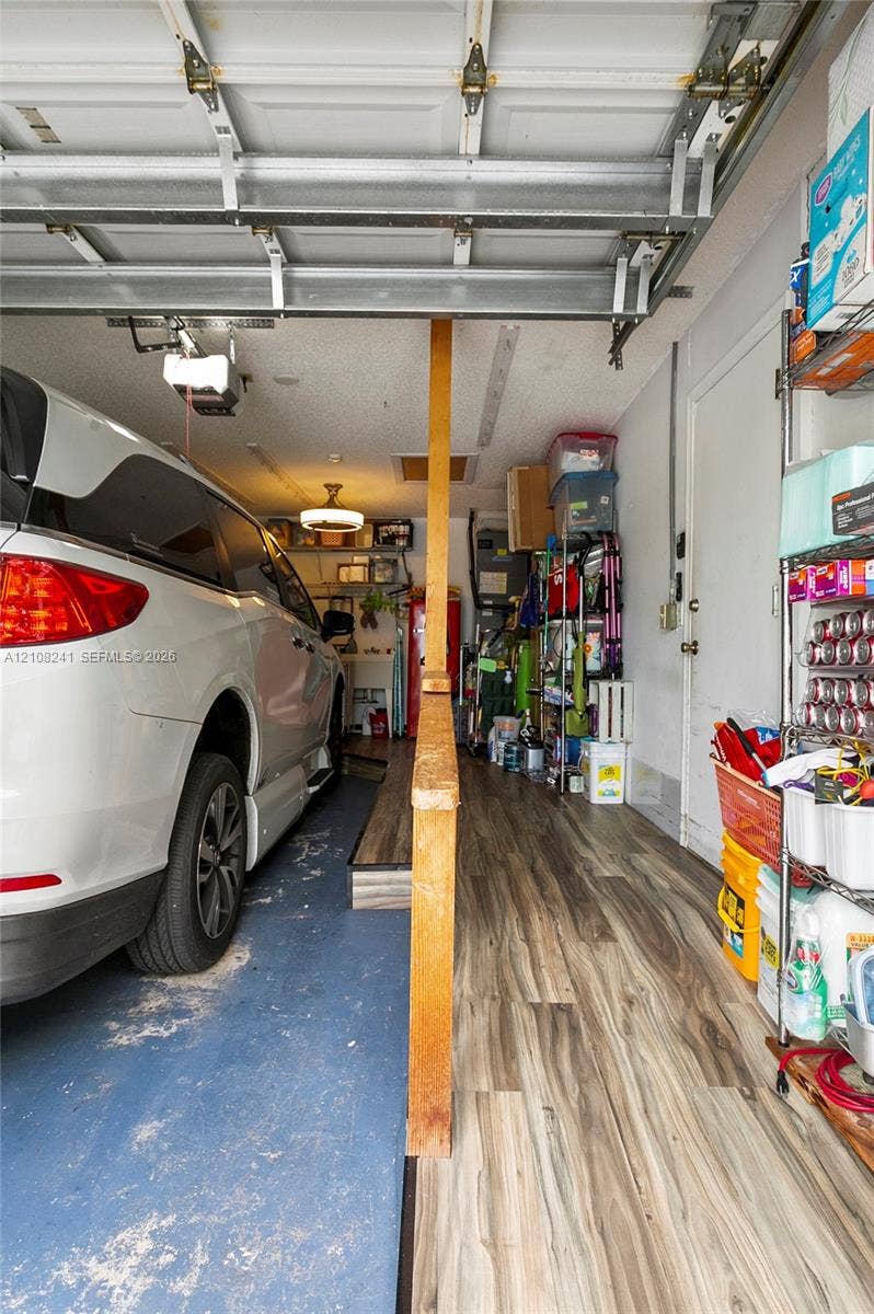 Garage featuring painted concrete flooring, wood-finish flooring, and a central wood support post