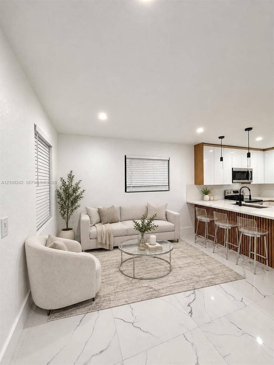 61 E 39th Street, Hialeah, FL 33013 Kitchen area featuring white gloss cabinetry, vertical wood-slat island paneling, stone-finish countertops, recessed lighting, and large-format tile flooring