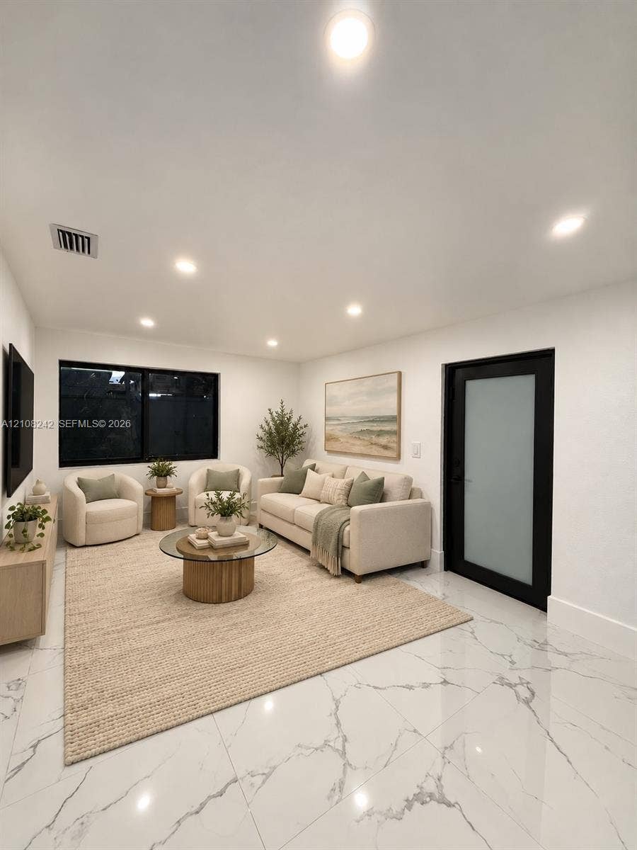 61 E 39th Street, Hialeah, FL 33013 Large-format tile flooring with marble-style veining, recessed lighting, and a modern door featuring a frosted glass panel and black frame