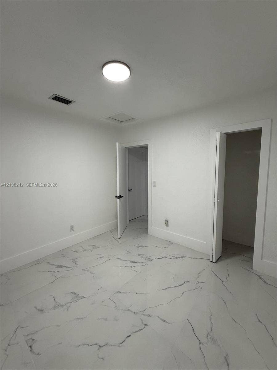 61 E 39th Street, Hialeah, FL 33013 Interior space featuring polished stone-finish flooring with marbled veining and a flush-mount ceiling light fixture
