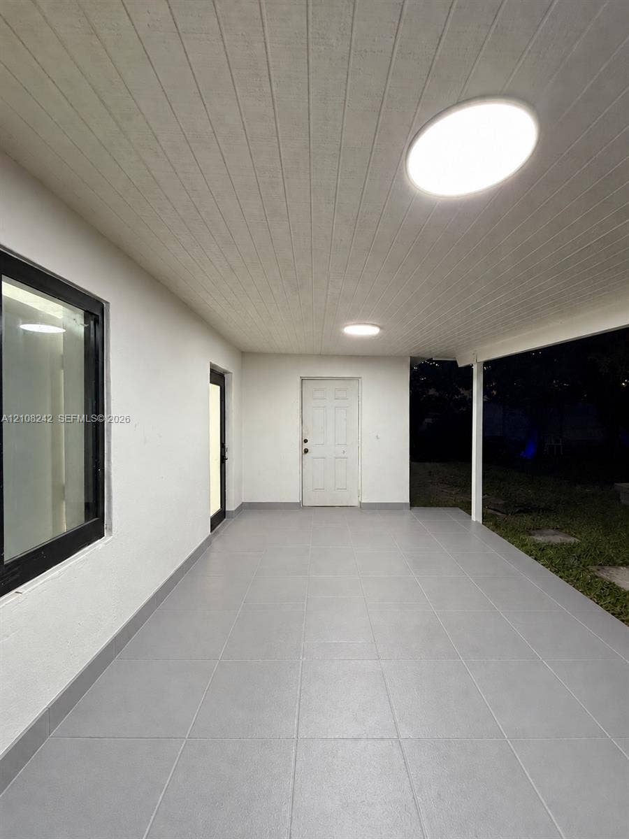 61 E 39th Street, Hialeah, FL 33013 Covered patio featuring large-format grey tile flooring, tongue-and-groove ceiling paneling, and flush-mount LED lighting