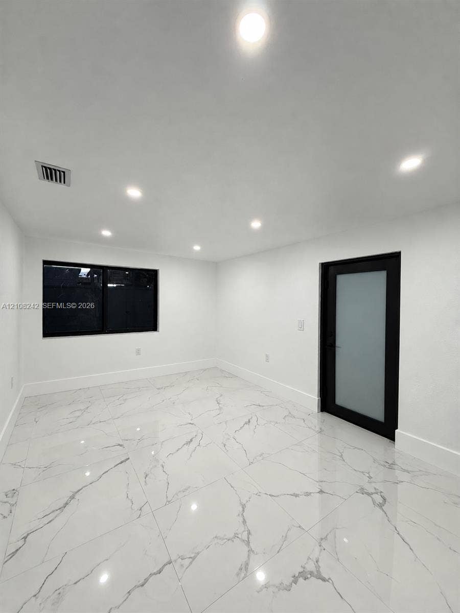 61 E 39th Street, Hialeah, FL 33013 Polished large-format tile flooring with vein detailing, recessed ceiling lighting, and a modern door featuring a frosted glass panel and black frame