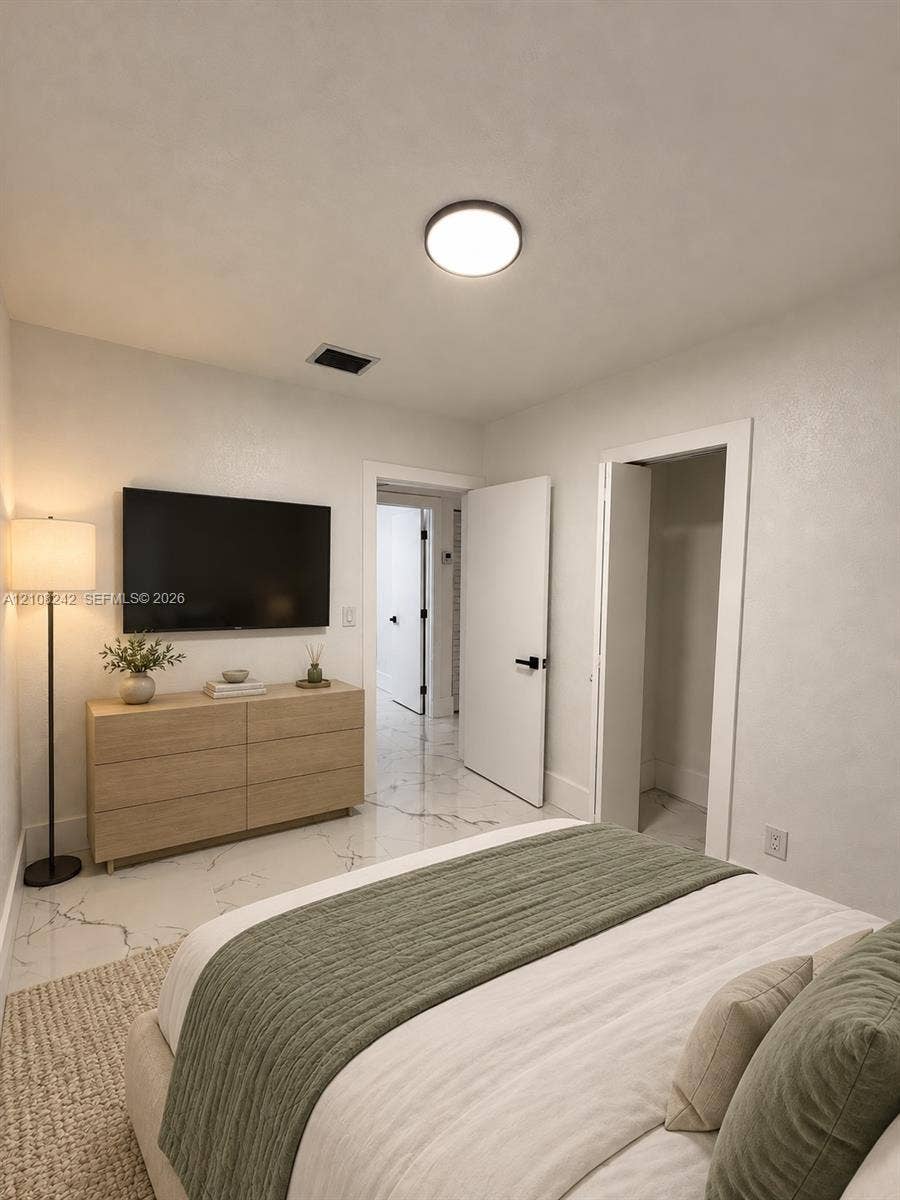 61 E 39th Street, Hialeah, FL 33013 Neutral-toned interior featuring large-format stone-finish tile flooring with veining, round flush-mount ceiling lighting, and solid-core doors with matte black hardware