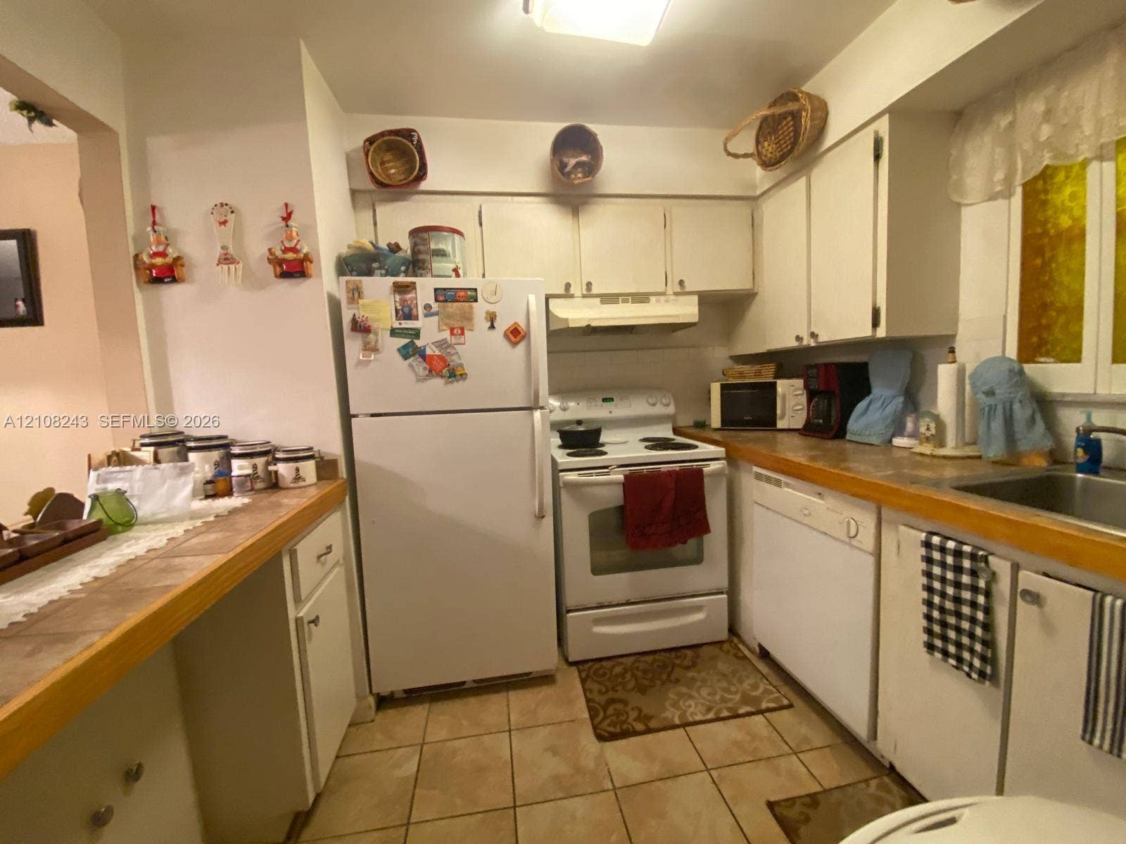 6505 Winfield Boulevard, #B-16, Margate, FL 33063 Kitchen featuring white cabinetry, solid-surface countertops, tile flooring, built-in range, and a drop-in stainless steel sink