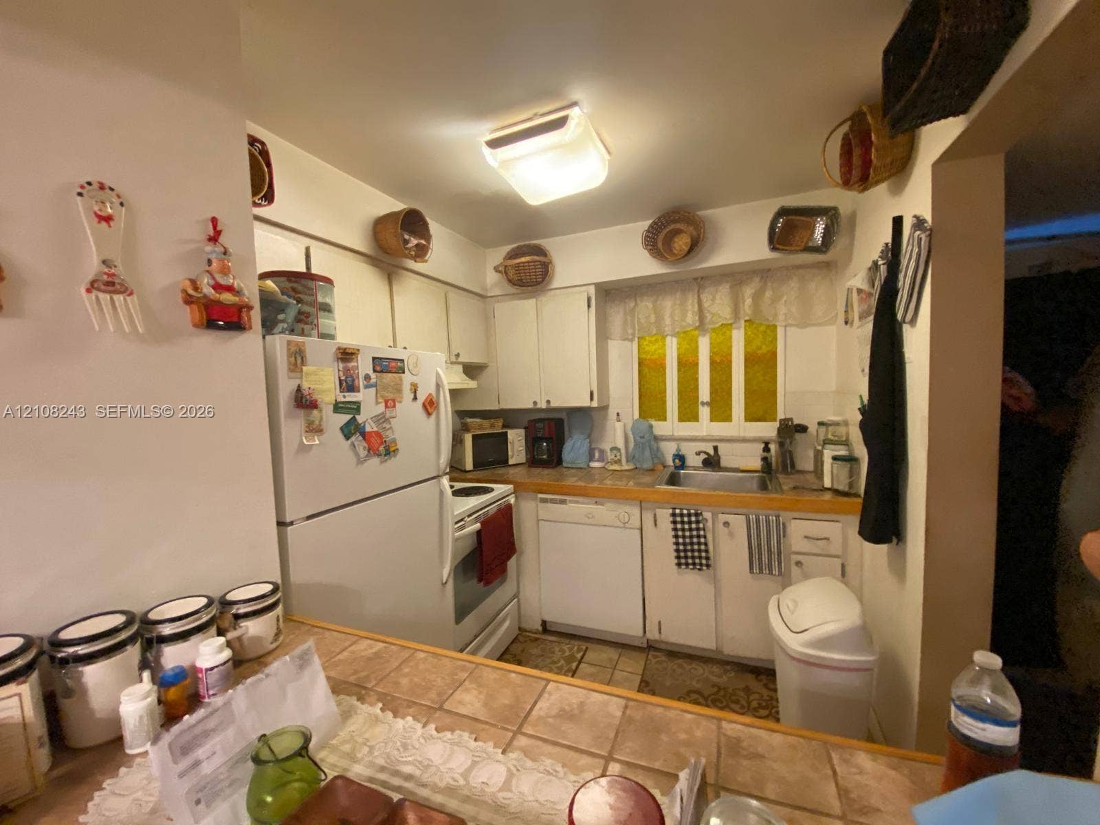 6505 Winfield Boulevard, #B-16, Margate, FL 33063 Kitchen featuring white cabinetry, tile-topped peninsula, integrated dishwasher, and multi-pane window
