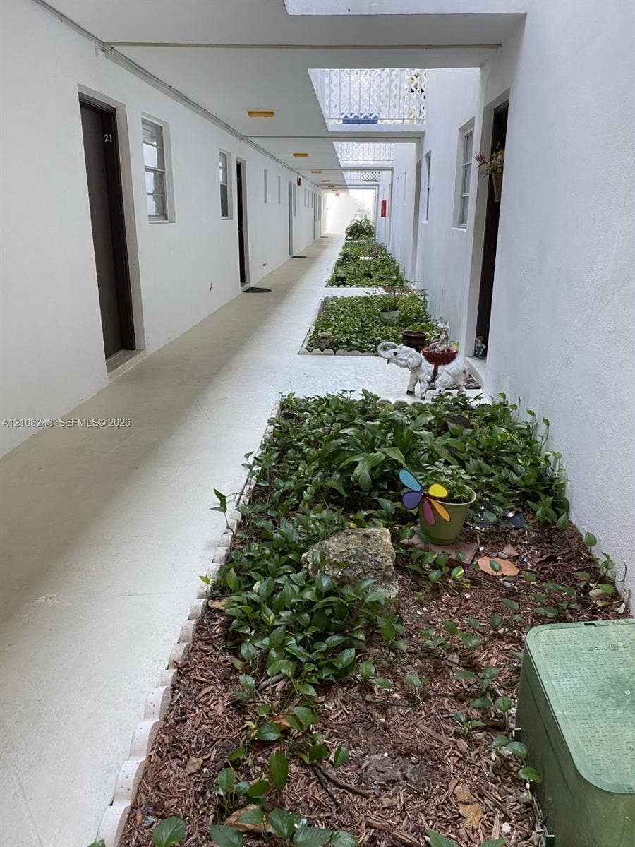 6505 Winfield Boulevard, #B-16, Margate, FL 33063 Open-air corridor featuring painted masonry walls, recessed lighting, and integrated landscape beds with scalloped stone edging