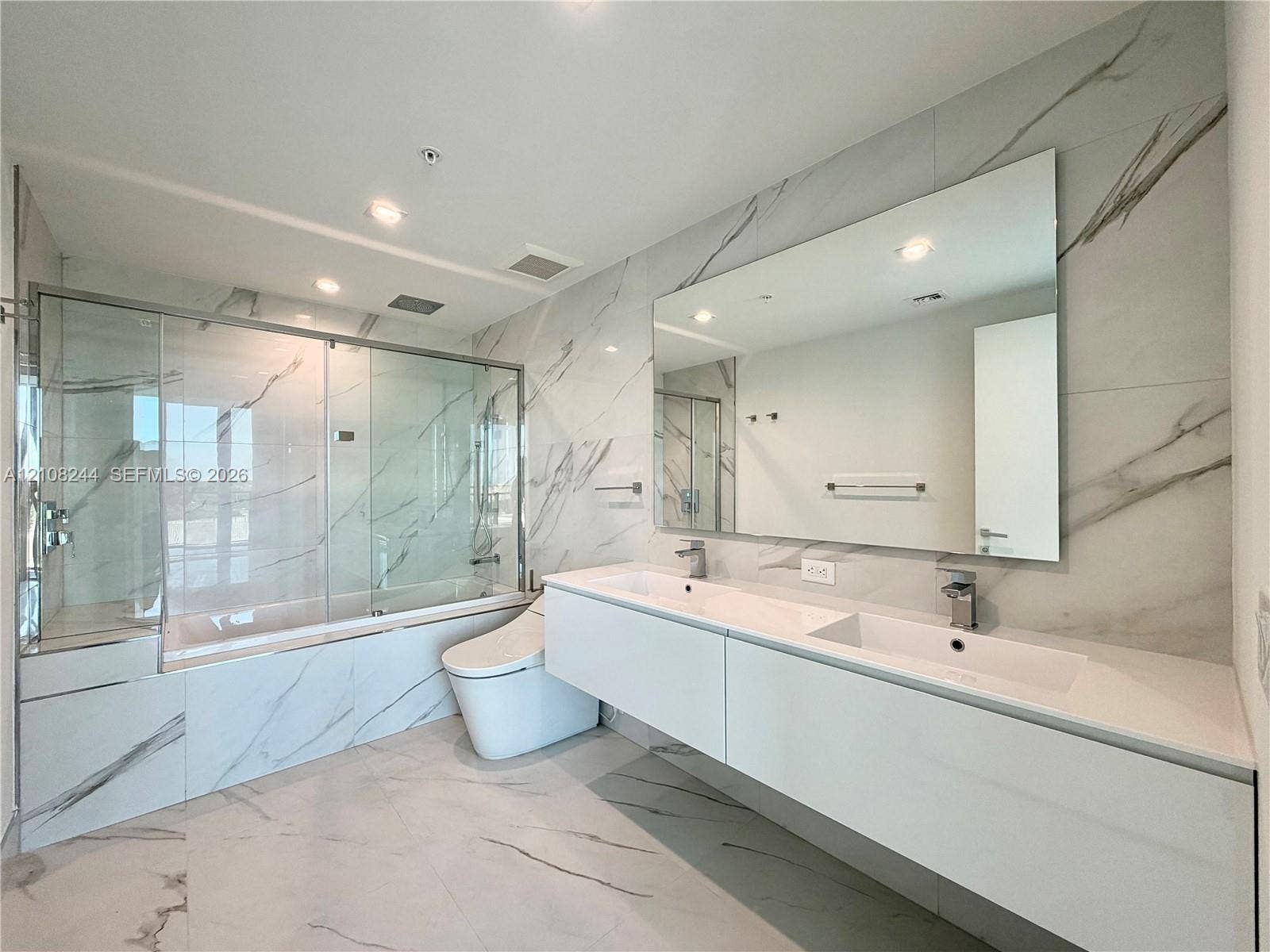 1170 Hallandale Beach Boulevard, #605, Hallandale Beach, Hallandale Beach, FL 33009 High-ceiling interior featuring stone-finish tile flooring with veining detail, recessed lighting, and white louvered-panel closet doors