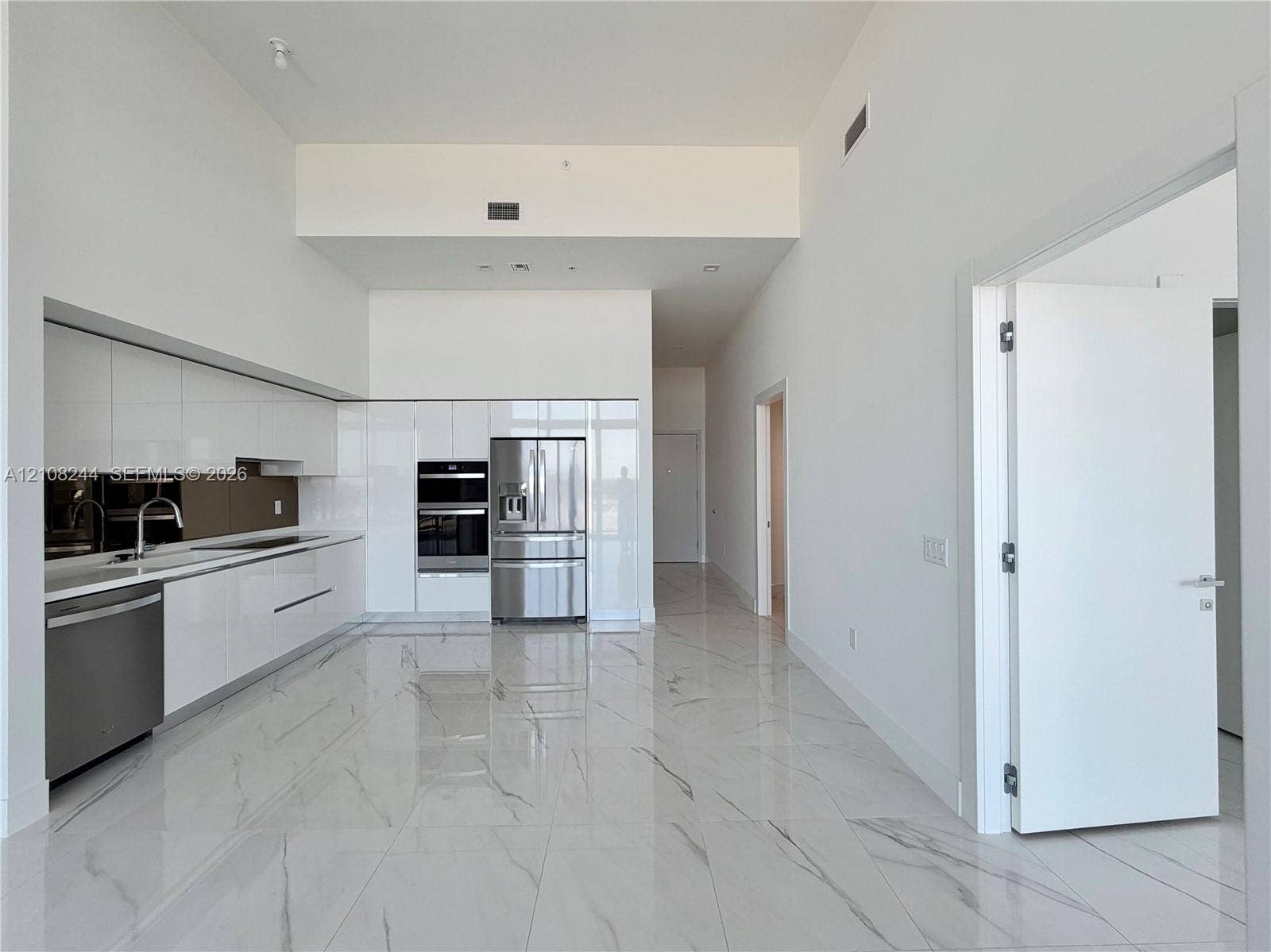 1170 Hallandale Beach Boulevard, #605, Hallandale Beach, Hallandale Beach, FL 33009 High-ceilinged interior featuring floor-to-ceiling windows with black metal frames, polished stone-finish tile flooring, and a glass-paneled balcony
