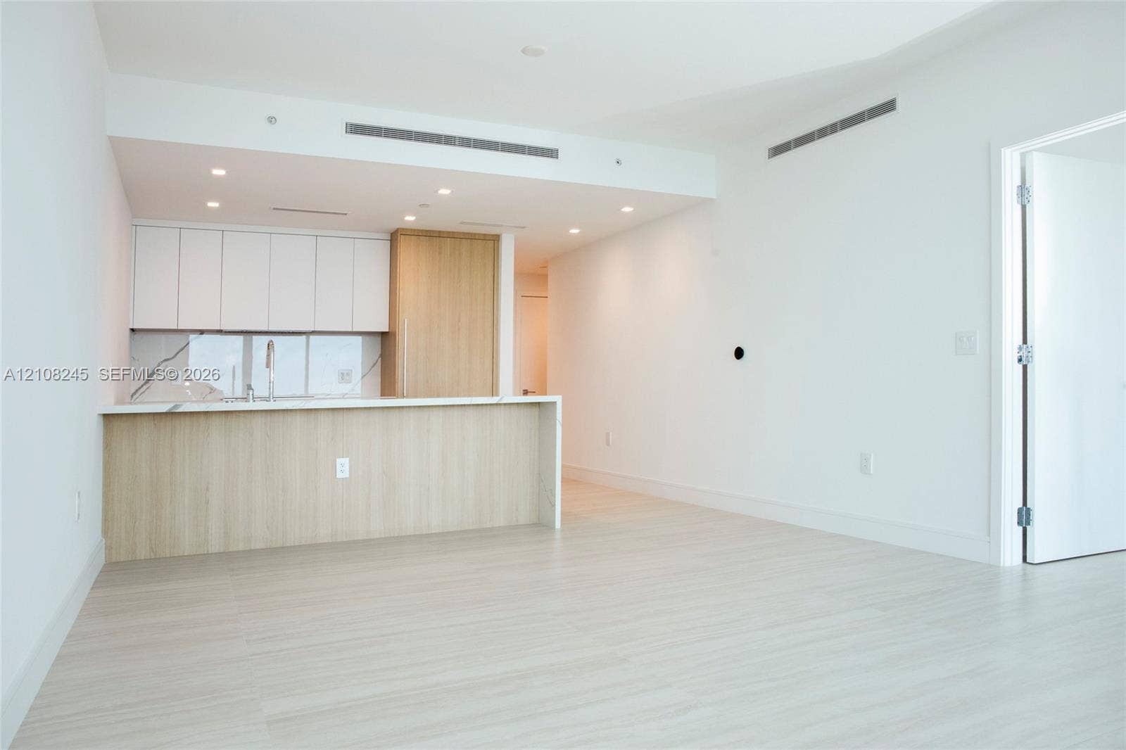 Kitchen featuring flat-panel cabinetry with wood-finish and white matte upper storage, stone-patterned backsplash, quartz countertop, and recessed ceiling lighting