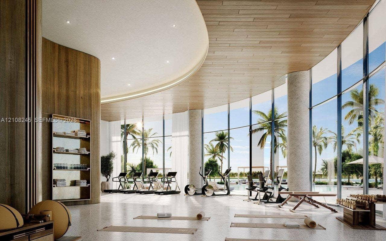 Floor-to-ceiling curved glass walls, expansive wood-paneled ceiling, recessed lighting, built-in shelving, and stone-finish flooring