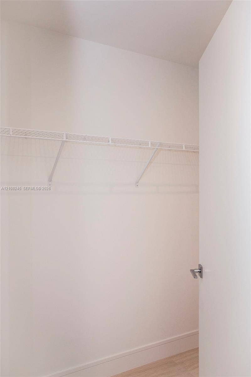 Storage space featuring a white wire shelving system, a mounted garment rod, and neutral flooring