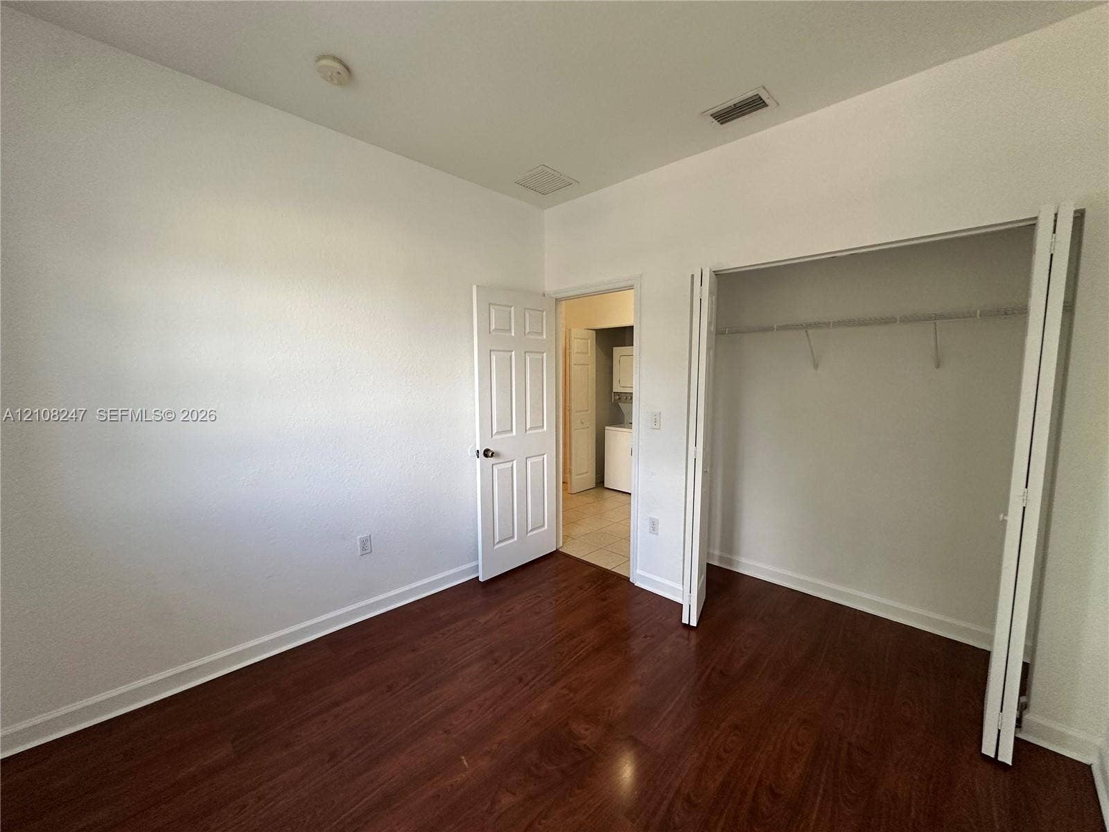2641 NE 4th Street, #204, Homestead, Homestead, FL 33033 Interior space featuring wood-finish flooring, a bi-fold door closet with built-in shelving, and a six-panel interior door