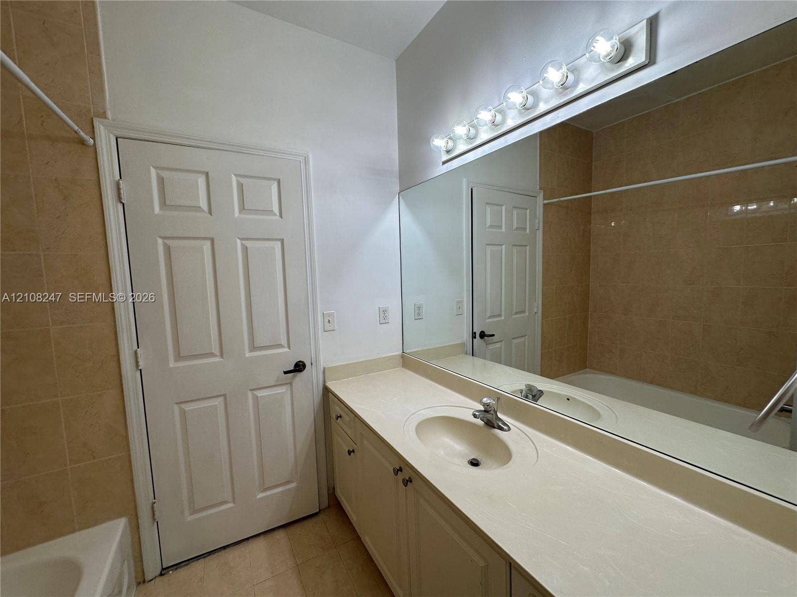 2641 NE 4th Street, #204, Homestead, Homestead, FL 33033 Full-width wall mirror, vanity cabinet with integrated countertop and sink, six-bulb light fixture, and floor-to-ceiling tiled shower enclosure