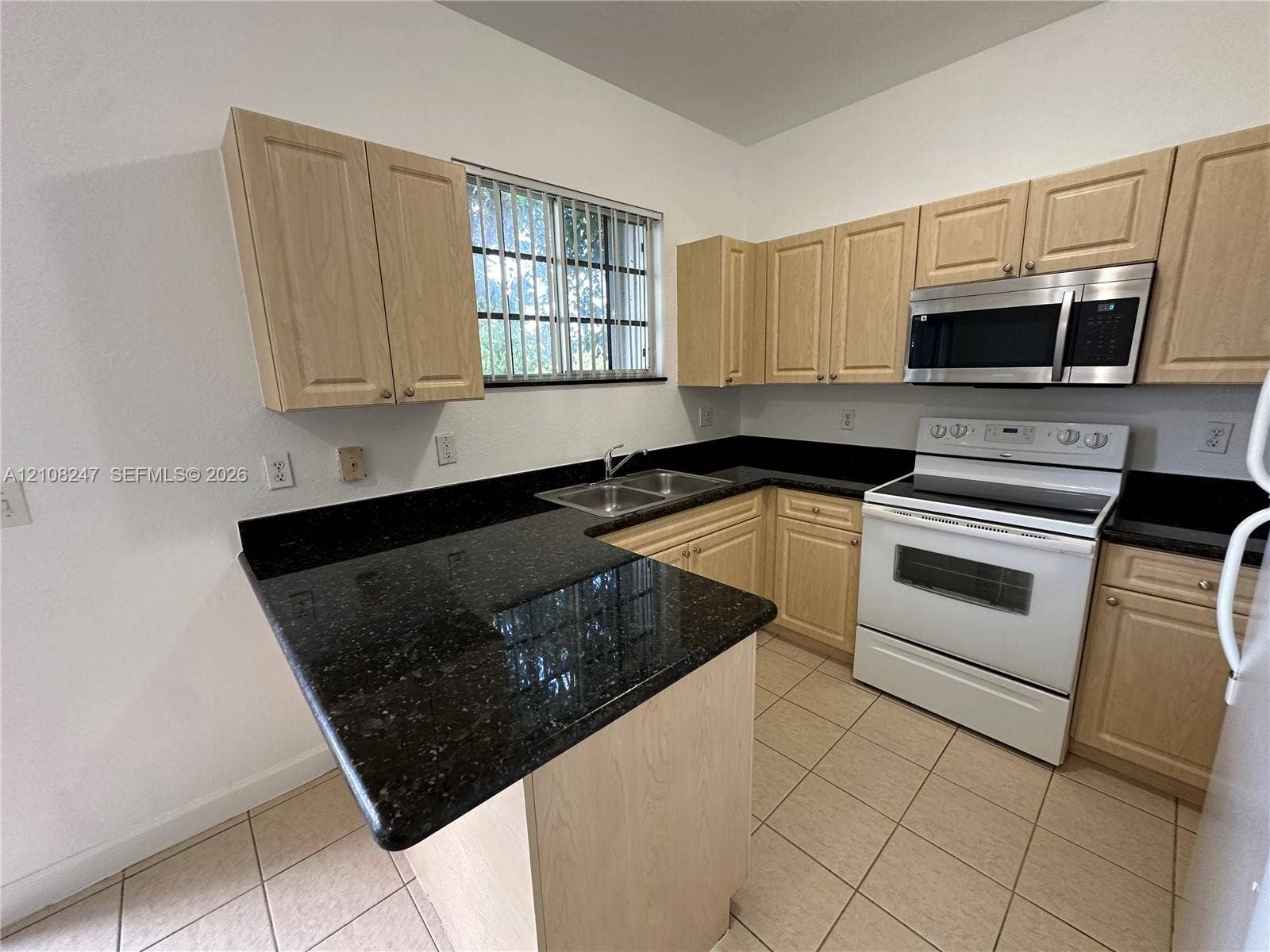 2641 NE 4th Street, #204, Homestead, Homestead, FL 33033 Kitchen featuring light-finish cabinetry, dark solid-surface countertops, dual-basin stainless steel sink, over-the-range microwave, and ceramic tile flooring
