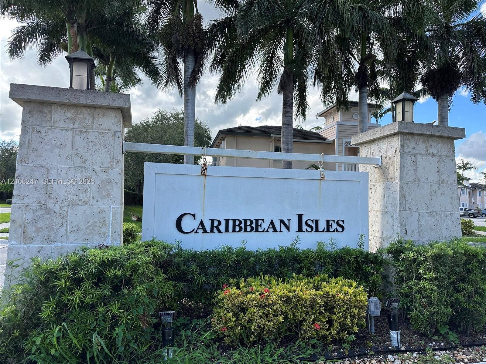 2641 NE 4th Street, #204, Homestead, Homestead, FL 33033 Community entrance featuring dual stone-clad pillars, attached lanterns, and mature palm trees