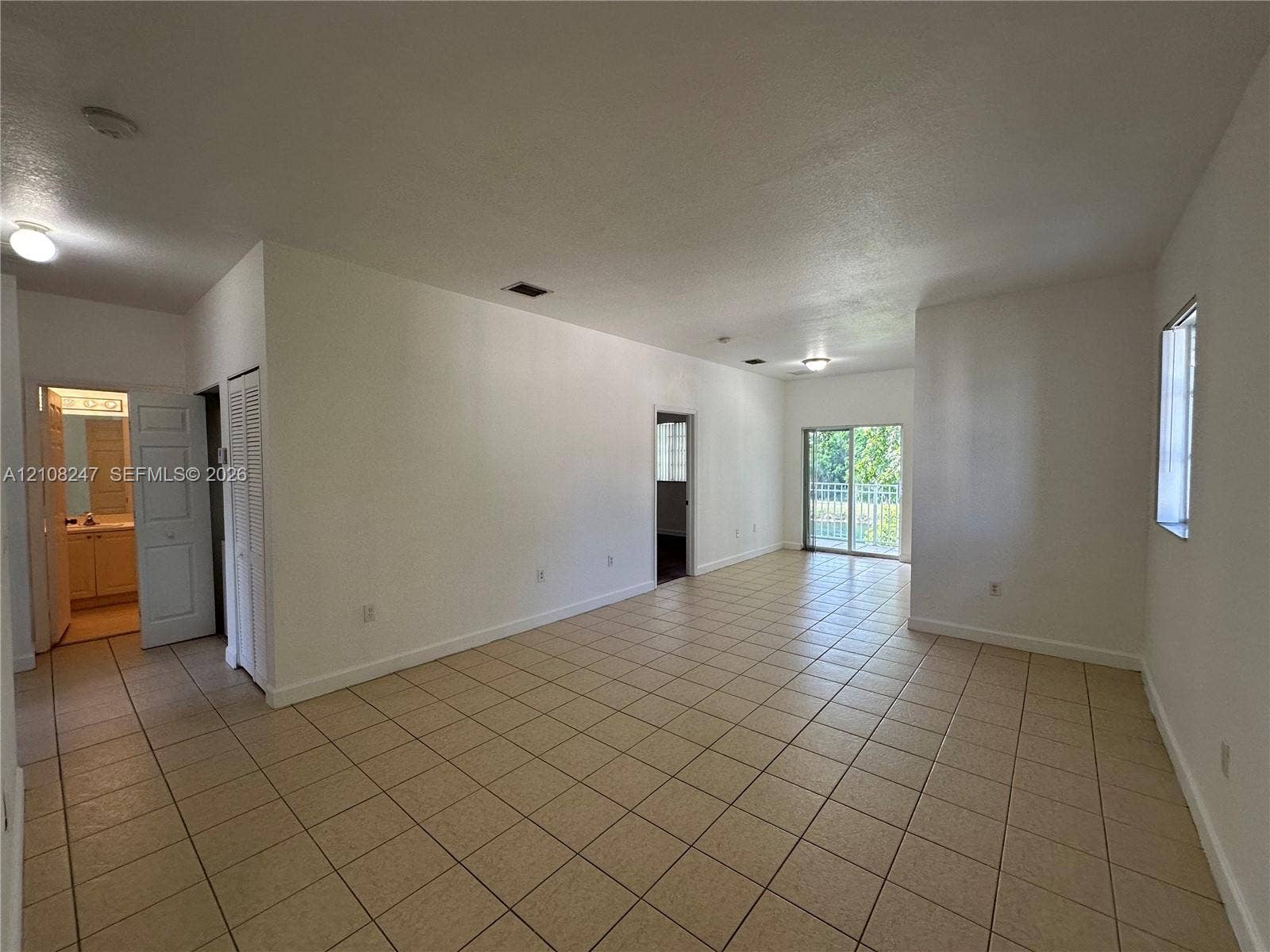 2641 NE 4th Street, #204, Homestead, Homestead, FL 33033 Open-concept interior featuring neutral tile flooring, sliding glass doors, and flush-mount ceiling lighting