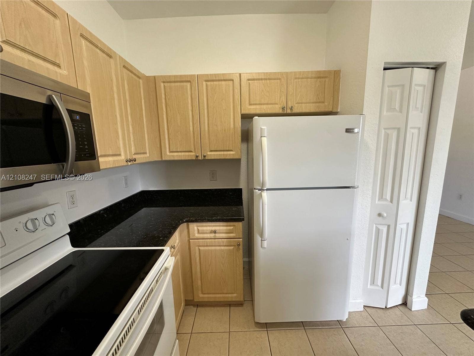 2641 NE 4th Street, #204, Homestead, Homestead, FL 33033 Kitchen featuring light-finish cabinetry, dark stone-style countertops, white appliance suite, and ceramic tile flooring