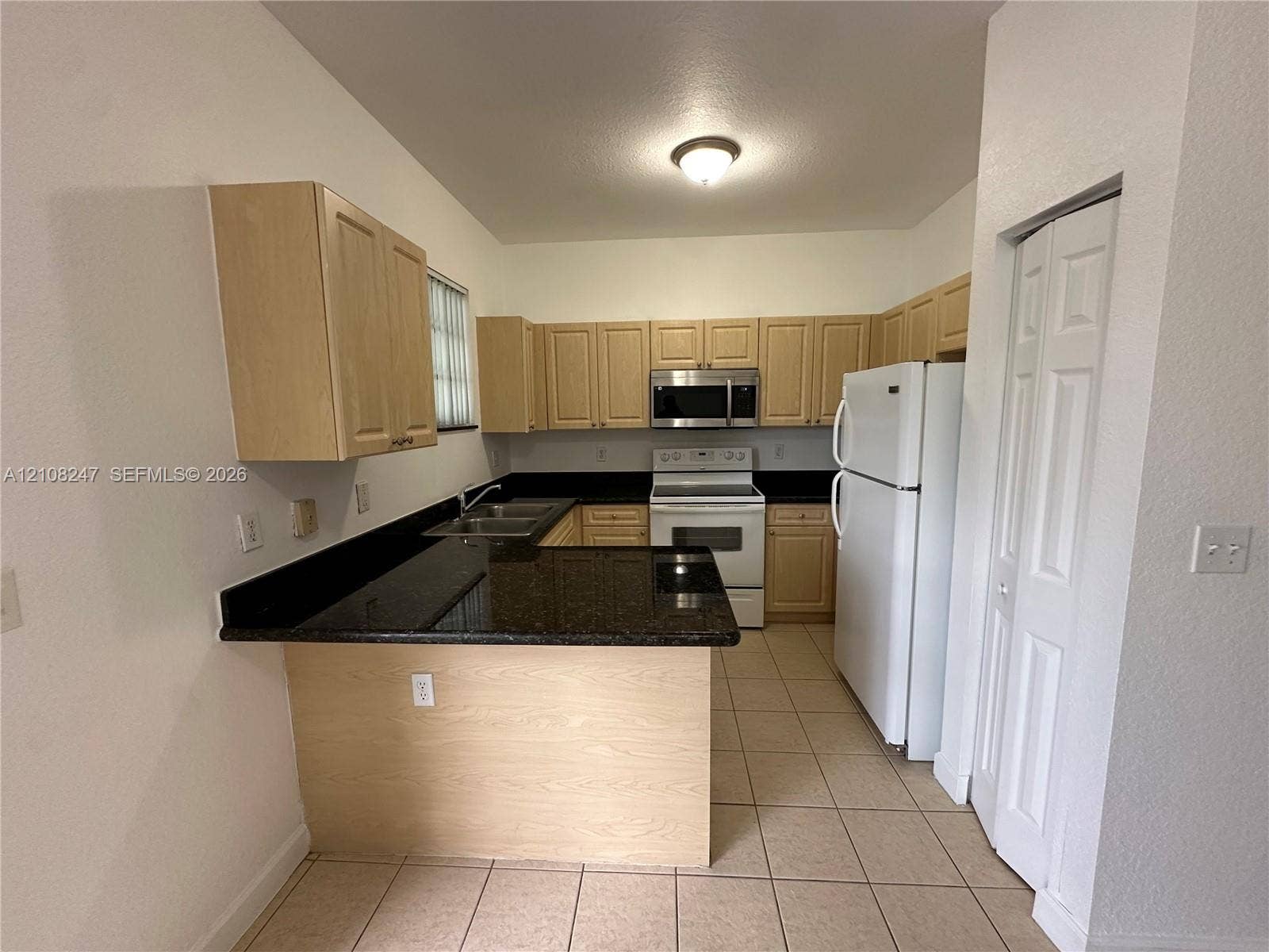 2641 NE 4th Street, #204, Homestead, Homestead, FL 33033 Kitchen featuring light-finish cabinetry, dark solid-surface countertops, tile flooring, and integrated white appliances