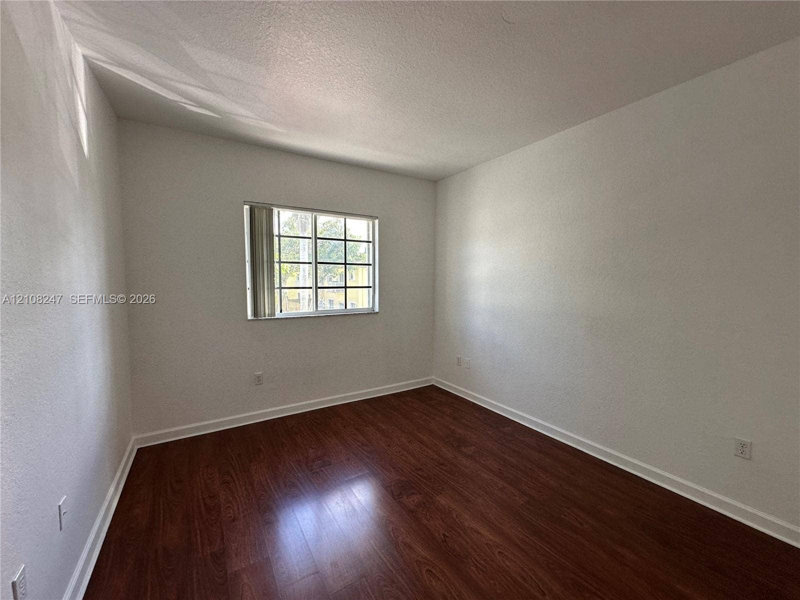 2641 NE 4th Street, #204, Homestead, Homestead, FL 33033 Neutral-toned walls paired with wood-finish flooring and a multi-pane window featuring vertical blinds