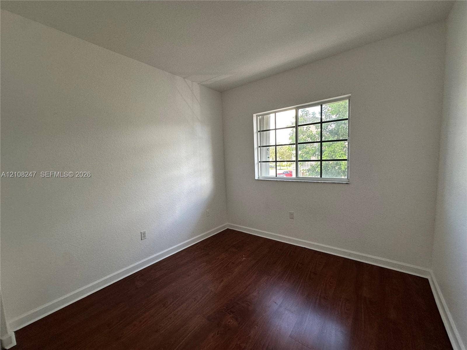 2641 NE 4th Street, #204, Homestead, Homestead, FL 33033 Room featuring wood-finish flooring, white walls, and a multi-pane sliding window