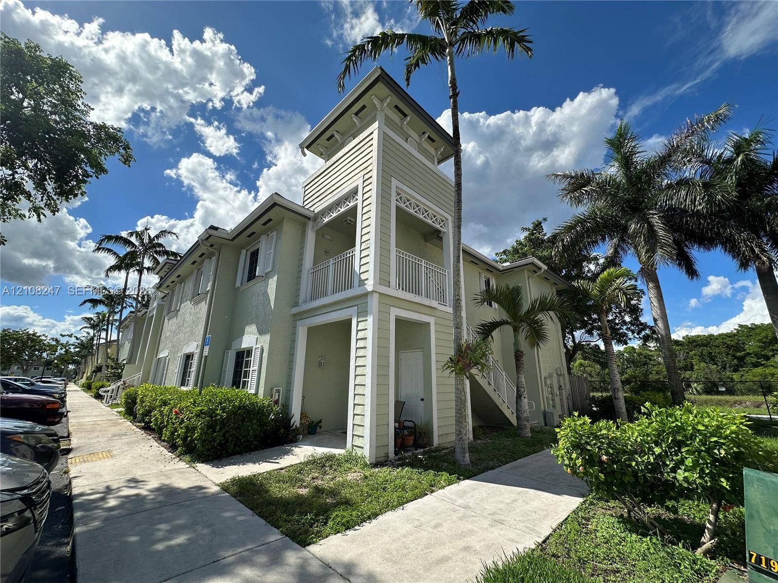 2641 NE 4th Street, #204, Homestead, Homestead, FL 33033 Two-story building featuring horizontal lap siding, a decorative cupola, private balconies with white railings, and an exterior staircase