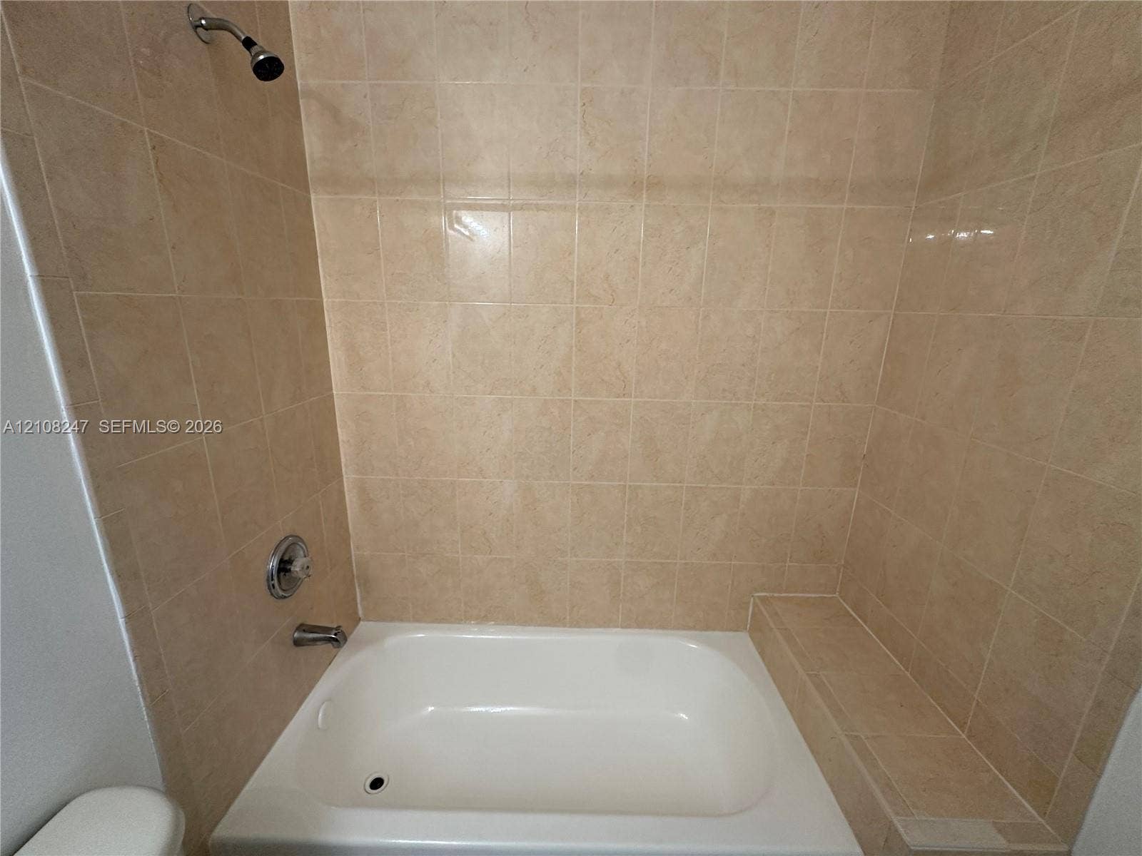 2641 NE 4th Street, #204, Homestead, Homestead, FL 33033 Bathtub featuring a built-in tiled ledge, neutral wall-to-wall ceramic tile surround, and metallic shower hardware