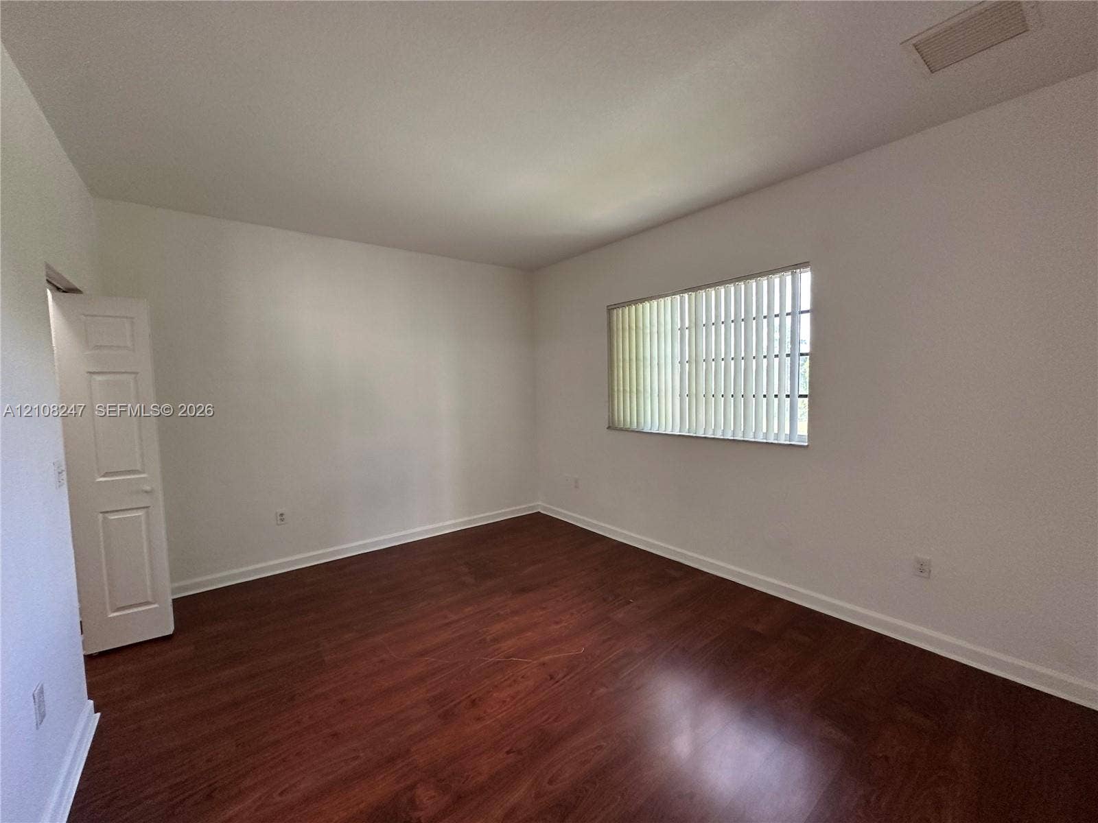 2641 NE 4th Street, #204, Homestead, Homestead, FL 33033 Interior room featuring wood-finish flooring, a single-panel interior door, and a horizontal window with vertical blinds