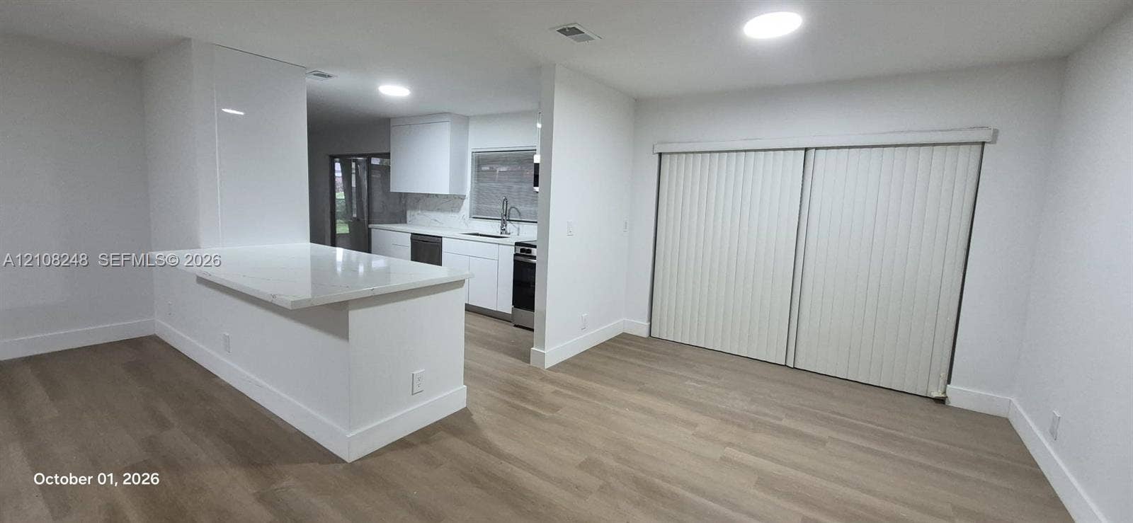 4490 Pine Garden Lane, Lake Worth, FL 33467 Kitchen featuring white cabinetry, stone-finish countertops, stainless steel appliances, wood-finish flooring, and sliding glass doors