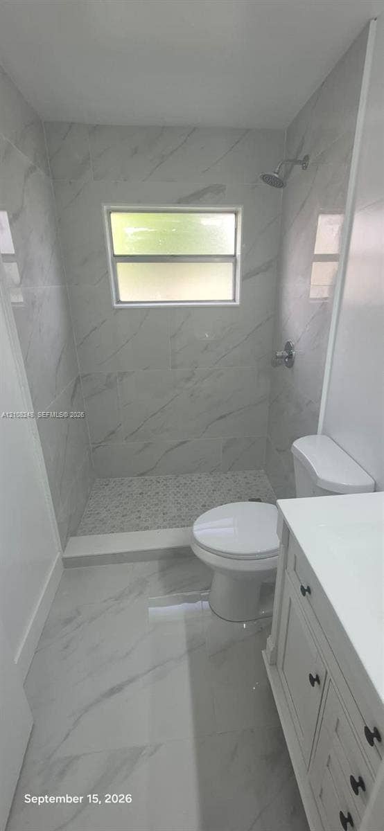 4490 Pine Garden Lane, Lake Worth, FL 33467 Walk-in shower featuring floor-to-ceiling stone-pattern tile, mosaic tile flooring, a window, and a built-in vanity with a solid-surface countertop
