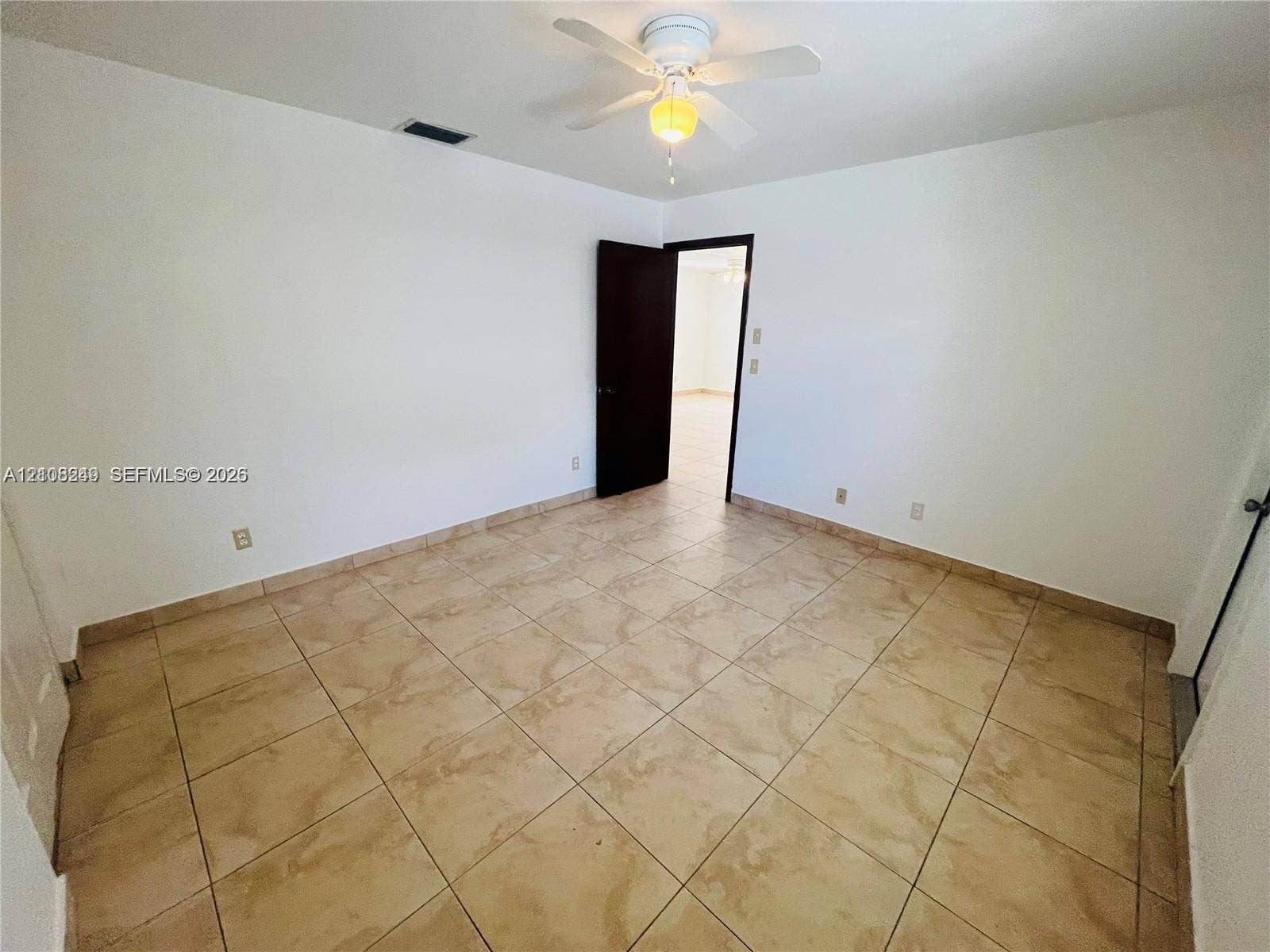 Room featuring neutral wall finishes, tile flooring, and a ceiling-mounted light fixture with a fan