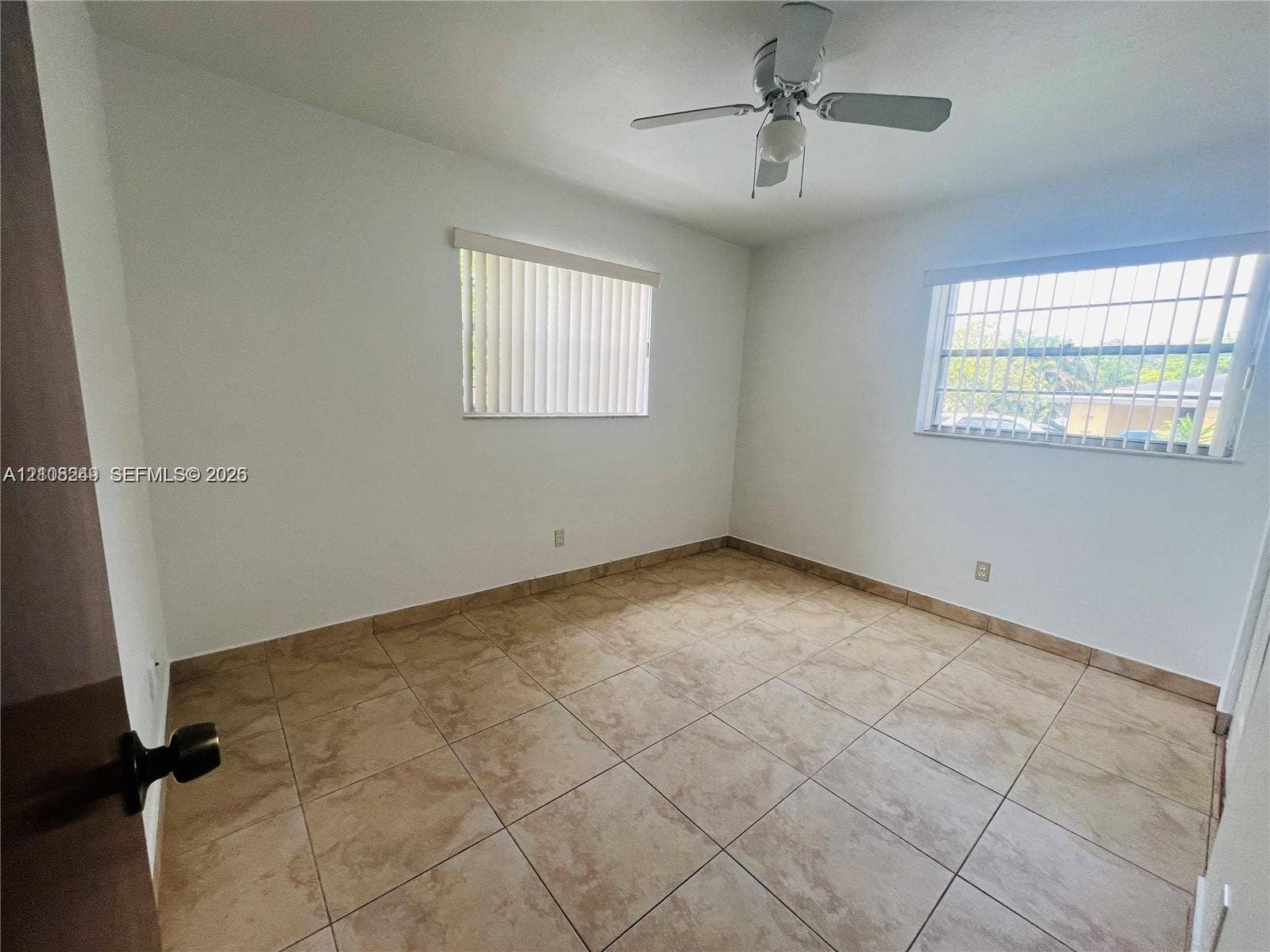 Room featuring tile flooring, ceiling fan with integrated lighting, and horizontal blinds on windows
