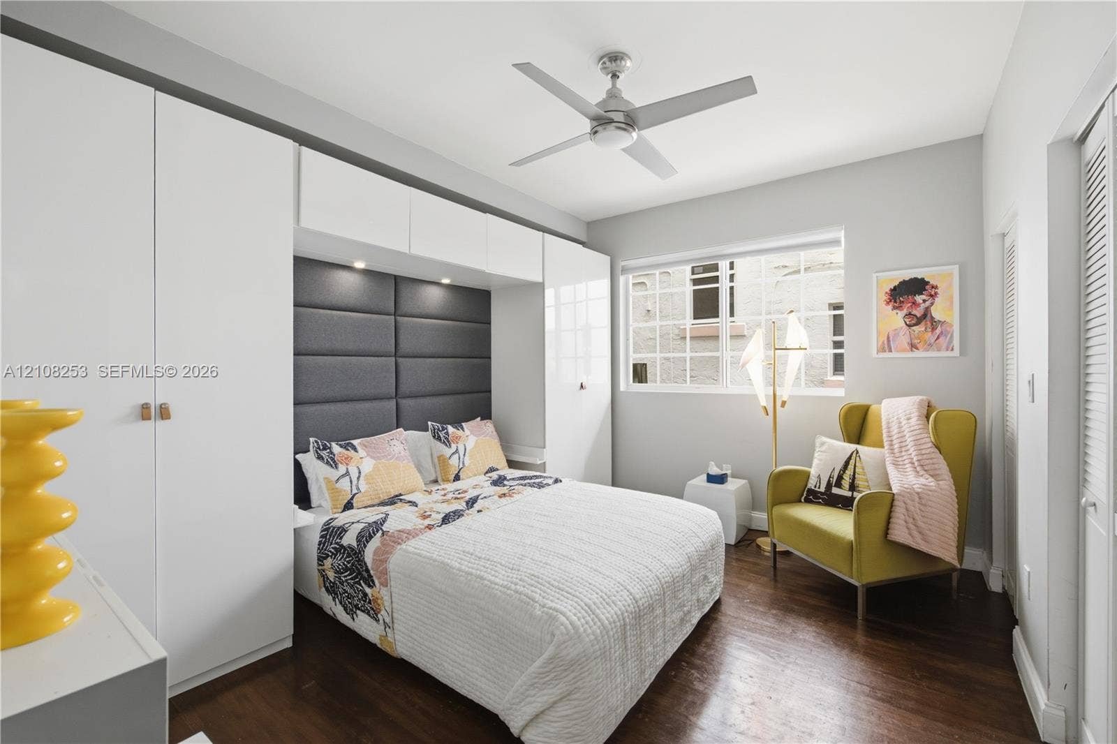 1330 Drexel Avenue, #102, Miami Beach, FL 33139 Room featuring dark wood-finish flooring, built-in white cabinetry, integrated recessed lighting, a charcoal grey upholstered headboard, and a multi-blade ceiling fan