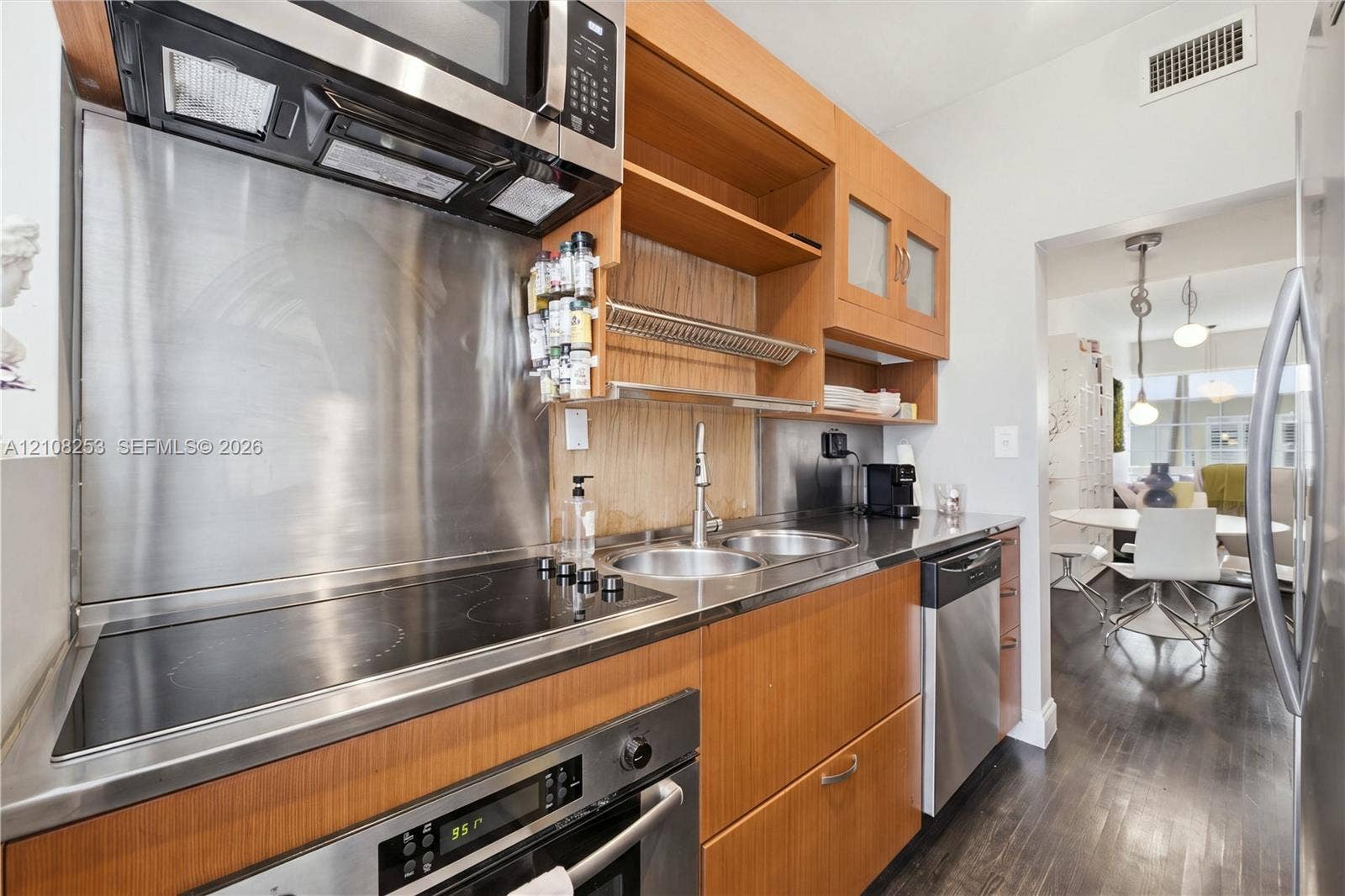 1330 Drexel Avenue, #102, Miami Beach, FL 33139 Kitchen featuring wood cabinetry, stainless steel appliances, electric cooktop, integrated stainless steel backsplash, and double-basin sink